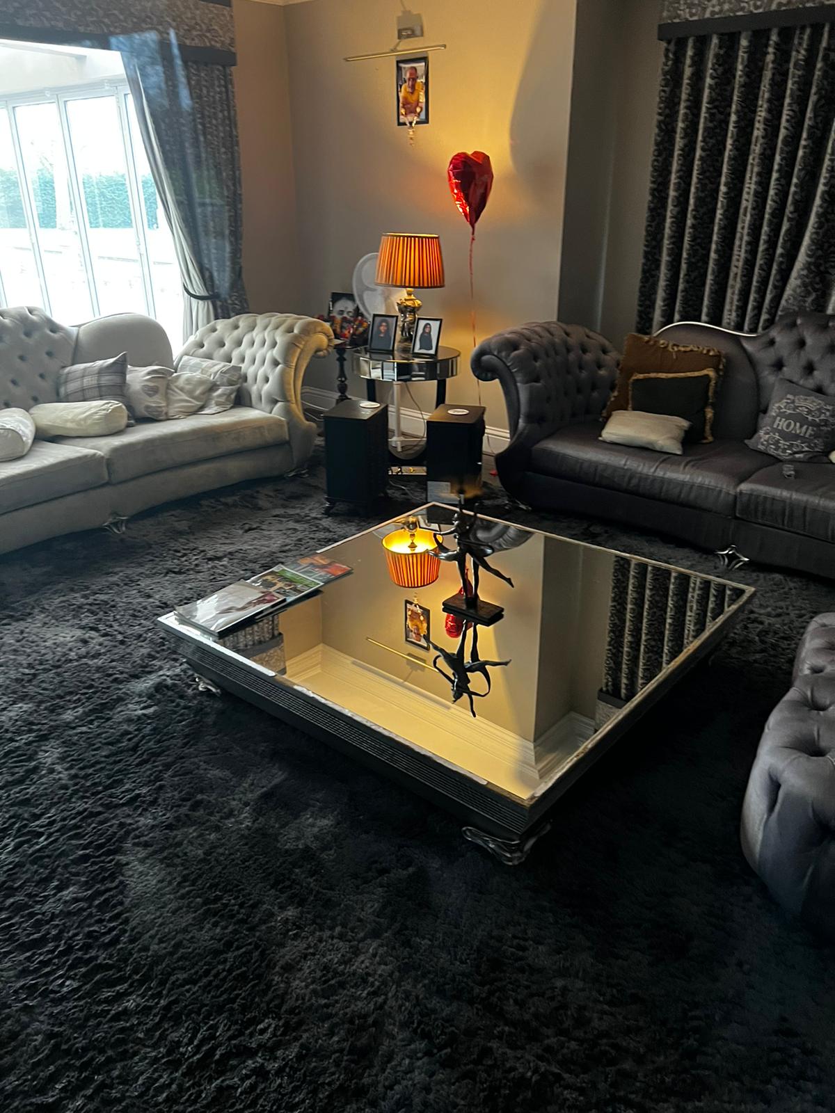 Luxury living room with chesterfield sofas and mirrored coffee table in a UK home